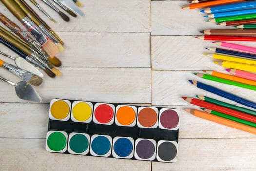 Set of artist accessories collection. Canvas, tube of oil paint, art brushes, palette knife lying on the wood table. Artist workshop background.
