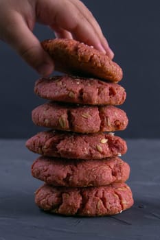 Child's hand reaching for fresh baked beet chip oatmeal cookies on a blectk table background. Holiday celebration and cooking concept. Selective focus.