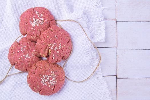 Beetroot oatmeal cookie stands on a white towel. Top views, close-up, clear space.