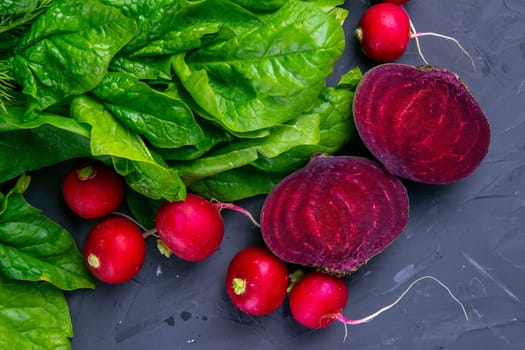Fresh vegetables and greens radish, spinach, beet on a black background. Top views, clouse-up