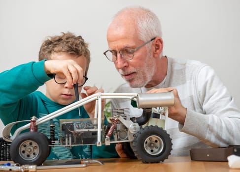 grandpa and son little boy repairing  model radio-controlled car at home
