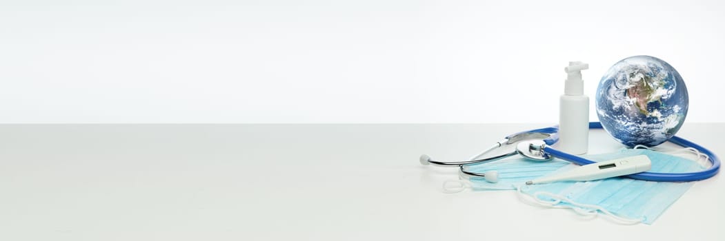 COVID-19. World globe with stethoscope, medical masks, sanitizer, thermometer. Global quarantine, infection prevention. Elements of this image furnished by NASA. Extra wide panorama banner background