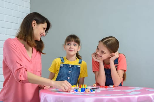 Girl made a funny face playing board games with mom and sister