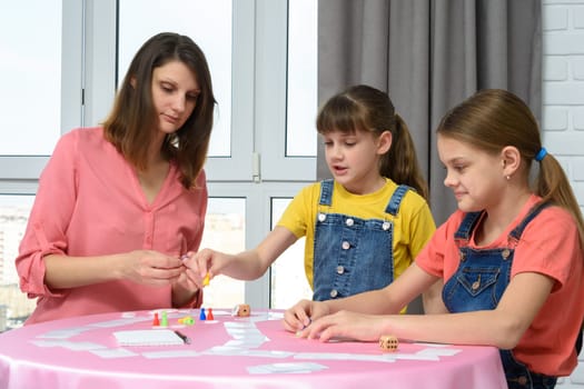 Mom and two daughters play board games at home on vacation