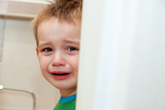 Portrait Of Crying Baby Boy In Home. Free space for text on the right.