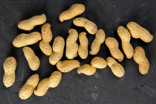 Peanuts on a dark background. Peanuts in a shell. Healthy food. top views, close-up.