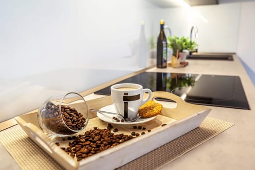 A tray of coffee with spilled coffee beans on a table. In the background is a blurred modern kitchen.