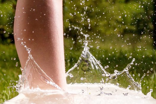 Little boy and splash of water in the summer garden - detail shot