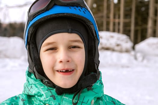 little boy on mountains in ski helmet with fallen first tooth, Czech Republic