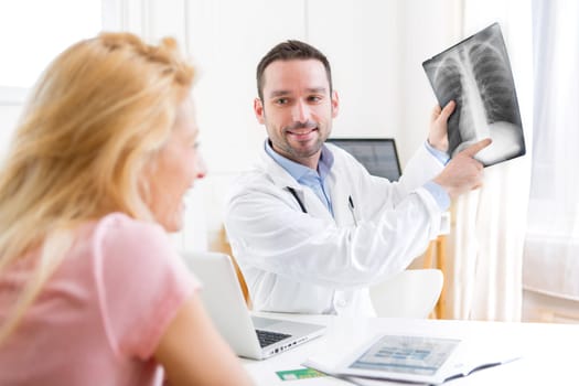 View of a Young attractive doctor analysing X-ray with patient