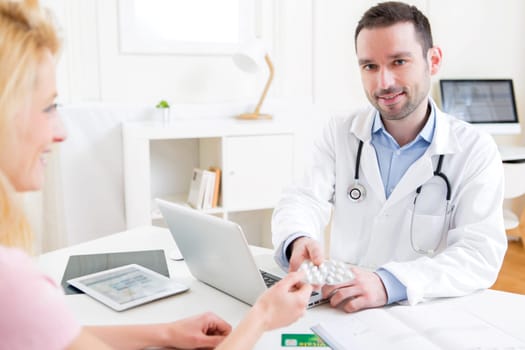 View of a Young attractive doctor giving pills to a patient
