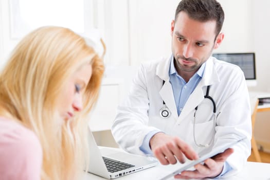 View of a Young doctor showing results on tablet to patient