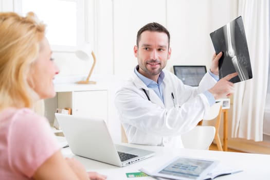 View of a Young attractive doctor analysing X-ray with patient