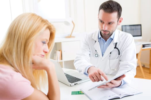 View of a Young doctor showing results on tablet to patient