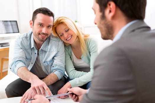 View of a Real estate agent present project on tablet to a young couple