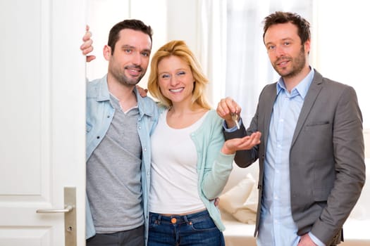 View of a Real estate agent delivers keys of new house to young couple