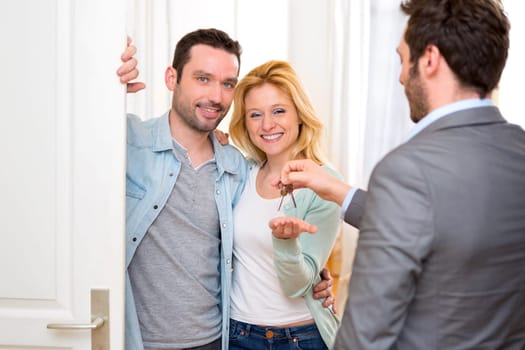 View of a Real estate agent delivers keys of new house to young couple