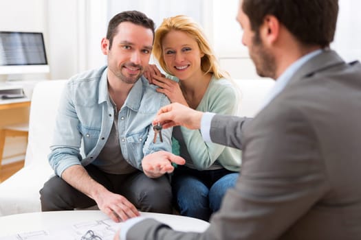 View of Real estate agent delivers keys of new house to young couple