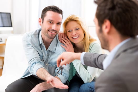 View of Real estate agent delivers keys of new house to young couple