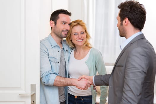 View of a Young happy couple handshaking real estate agent after signing contract