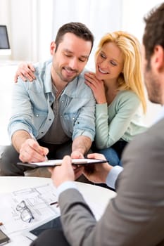 View of Young attractive couple signing contract with real estate agent