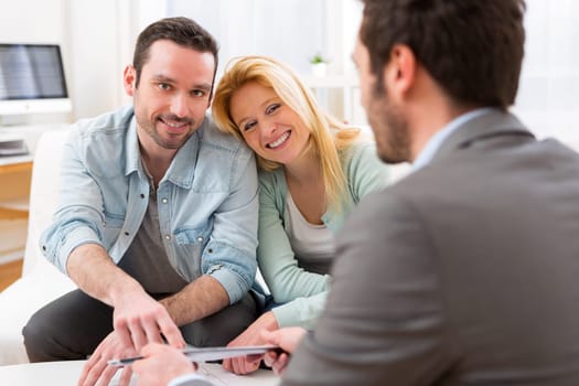 View of a Real estate agent present project on tablet to a young couple
