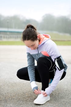 View of a Young attractive woman tying shoelaces before a running session