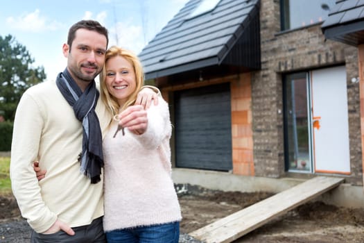 View of a Young happy couple in front of their future house