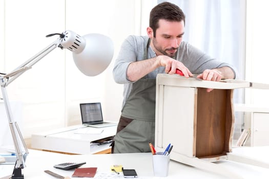 View of a Young attractive carpenter working in his workshop