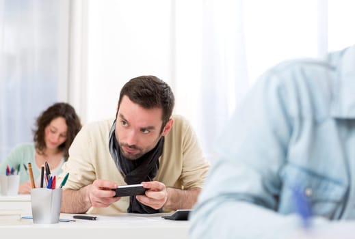 View of a Young attractive man cheating with mobile during exam