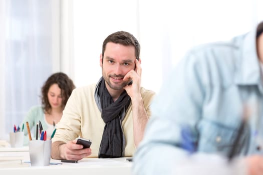 View of a Young attractive student using his mobile during classes