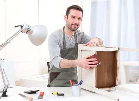 View of a Young attractive carpenter working in his workshop