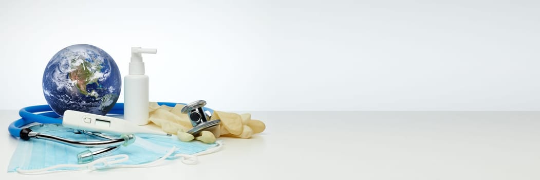 COVID-19. World globe with stethoscope, medical masks, sanitizer, thermometer. Global quarantine, infection prevention. Elements of this image furnished by NASA. Extra wide panorama banner background