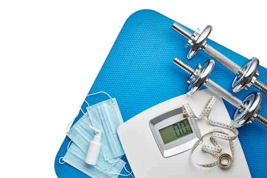 Sport equipment, scales, medical masks and sanitizer on white background. Top view, copy space. Fitness.  Isplation period. Weight and health control during quarantine. Concept of covid or coronavirus