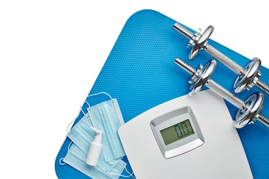 Sport equipment, scales, medical masks and sanitizer on white background. Top view, copy space. Fitness.  Isplation period. Weight and health control during quarantine. Concept of covid or coronavirus