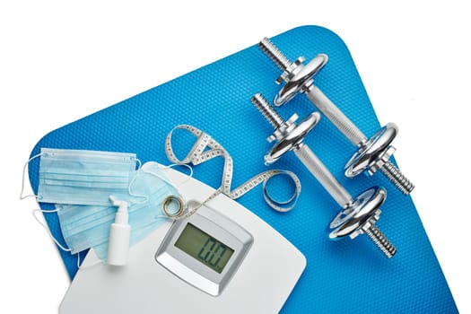 Sport equipment, scales, medical masks and sanitizer on white background. Top view, copy space. Fitness.  Isplation period. Weight and health control during quarantine. Concept of covid or coronavirus