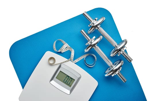 Dumbbells, blue mat and scales on white background. Planning of diet and trainings. Top view with copy space. Slimming. Sports bodybuilding equipment. Fitness, sport or healthy lifestyle concept.
