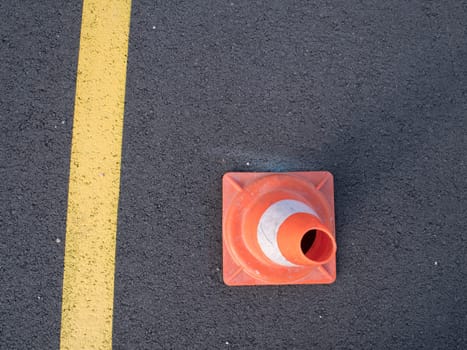 Traffic cone with shadow on asphalt. Traffic cone, with white and orange stripes on gray asphalt, copy space.