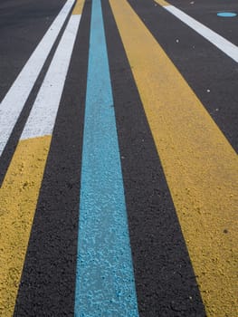 Various lines painted on asphalt. Yellow, blue, white. Part of a training ground for drivers.