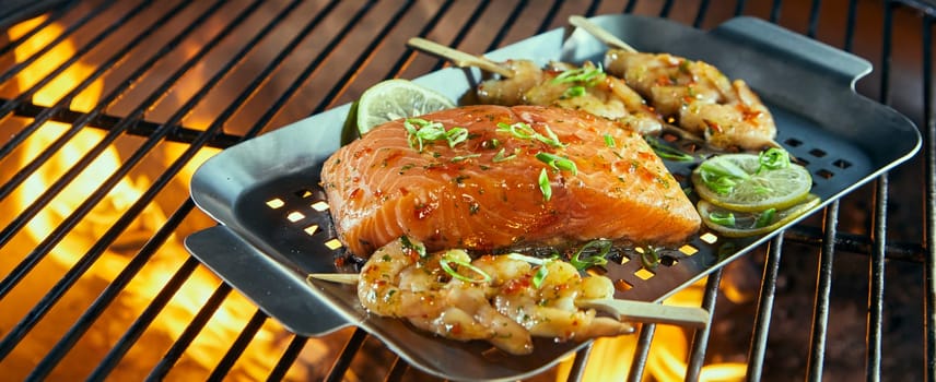 Fresh seafood for grilling over a barbecue with prawn kebabs and salmon steak ready seasoned wt herbs on a roasting pan