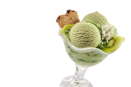 Speciality kiwifruit ice cream scoops with sliced fresh fruit for a delicious summer dessert served in a glass dish on white with copy space