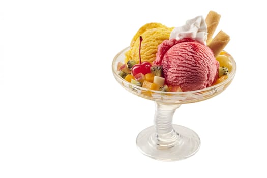 A colourful tropical ice-cream fruit sundae on a white background with copy space.