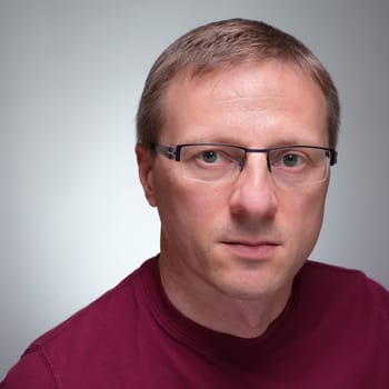Mann miMan with glasses and purple sweater and serious glimpse