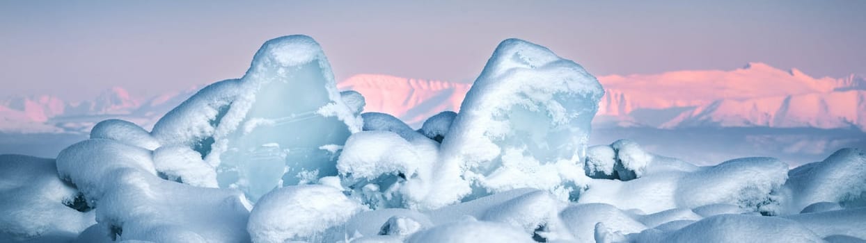 Transparent blue ice floes piled in ice hummocks against a blue sky on a sunny day. Unusual winter landscape of the frozen lake Baikal. Natural cold background. Siberia, Russia.