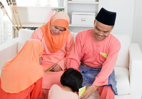 Asian Muslim Malay girl greeting to parents at home during hari raya. Malaysian people living lifestyle.