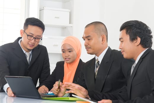 Group of Malaysian businesspeople meeting or having discussion on desk inside office room.