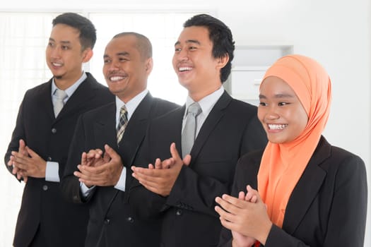 Group of business people standing in line clapping hands inside office room.
