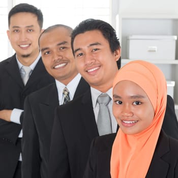 Group of Malaysian businesspeople standing in line inside office room.