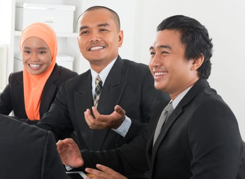 Group of Malaysian businesspeople meeting or having discussion on desk inside office room.