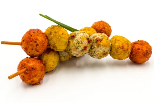 Marinated meatballs skewers on a wooden pick and a white background.